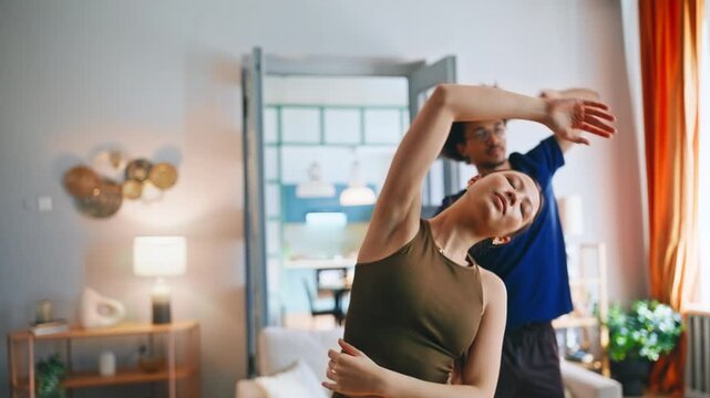 Couple doing side bend stretches together home living room closeup workout