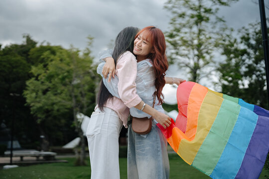 Happy Lesbian Couple Hugging with Rainbow Pride Flag Celebrating Love and Belonging