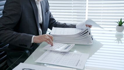 Businessman hands are organizing a large stack of financial documents and paperwork on a clean...