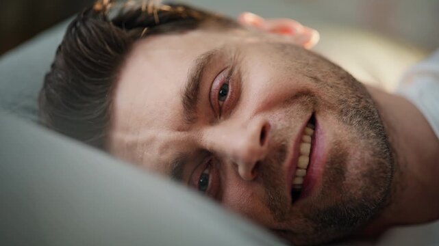 Close up sad man lying pillow thinking. Pensive tired guy face portrait indoors.