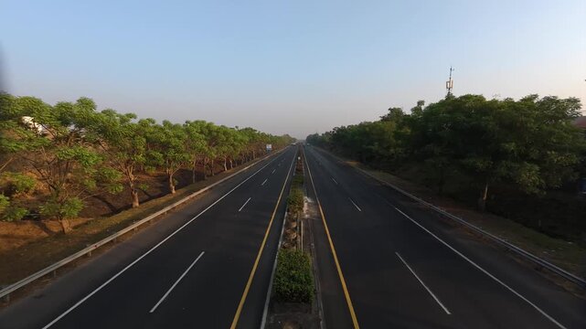 GRESIK, INDONESIA - JULY 19, 2026: High angle landscape timelapse of vehicles driving on a highway surrounded by green trees in the morning.