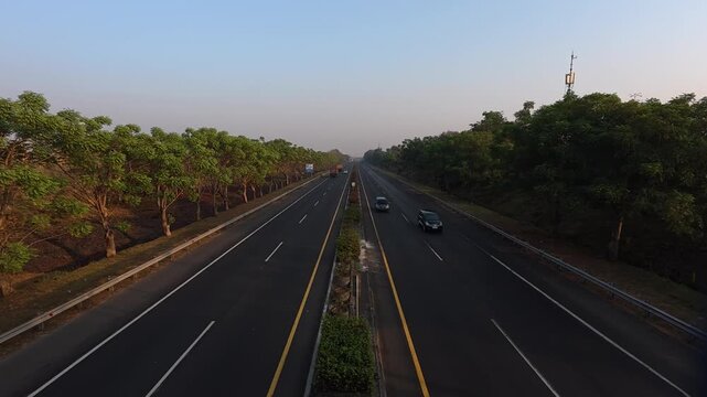 GRESIK, INDONESIA - JULY 19, 2026: High angle landscape shot of cars and buses driving on a relatively empty highway surrounded by green trees in the morning.