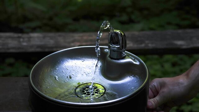 Arcing water stream at outdoor drinking fountain in shaded forest