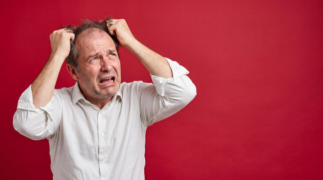 Man in white shirt pulling his hair in distress.
