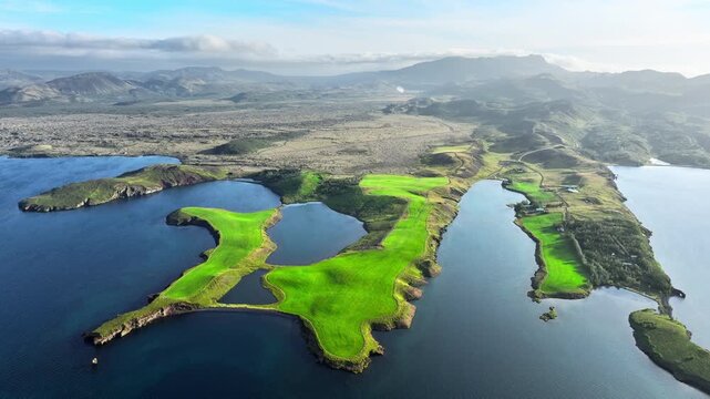 Oblique aerial motion of green peninsula with inland lakes and surrounding blue coastal waters captured from high viewpoint showing shoreline geometry and field contours