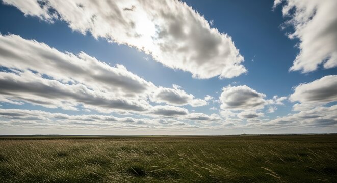 Cumulus fractus clouds over a grassy field under a bright sky