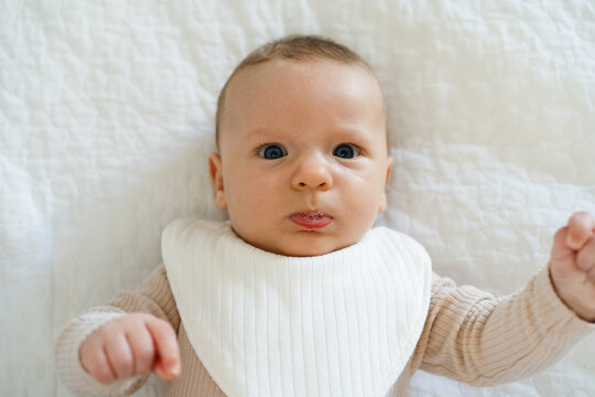 Portrait of a two to three month old baby with visible drool on lips. Natural process of infant development associated with increased saliva production in early infancy.