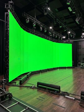 Large curved LED video wall with green screen. Professional studio stage for virtual production.