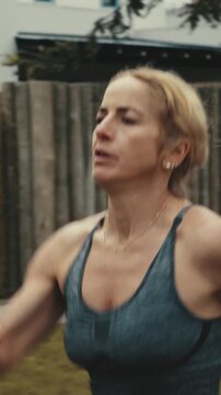 Close up of female runner's arms pumping past a wooden fence