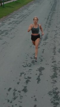 Elevated front view of female runner sprinting toward the camera