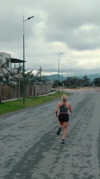 Elevated back view of female runner passing a wooden fence