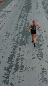 Elevated back view of female runner slowing to a walk