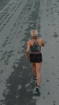 Elevated back view of braided female runner on a textured road