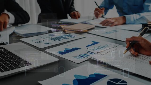 This image captures a professional business meeting with participants analyzing financial charts and data on a table. Laptops and documents create a dynamic collaboration atmosphere. Raster