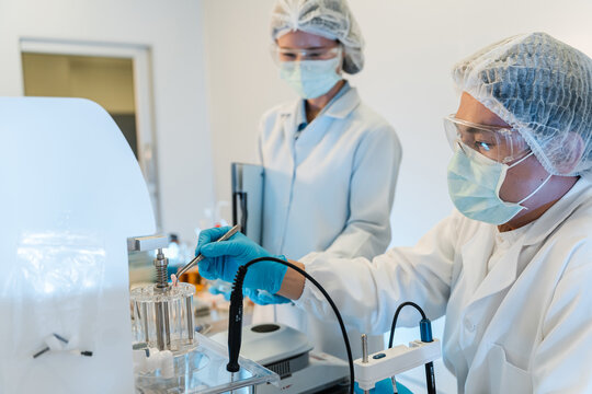 Scientists in lab attire handle equipment in a clean workspace. Asian scientists or researchers team working on medical and pharmaceutical development in a modern laboratory.