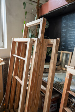 Several window frames stacked at carpentry workshop room after replacement of wooden parts, restoration of wooden items in woodworking studio, furniture renovation, handmade craft and reconstruction.
