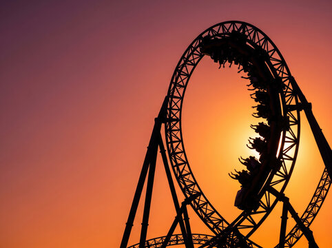 Roller coaster silhouette against a beautiful golden sunset sky at amusement park