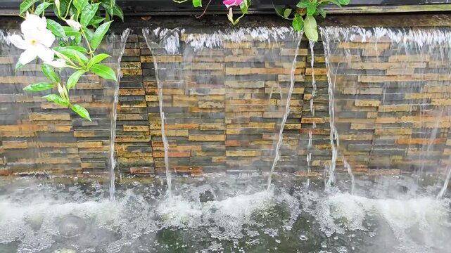 Natural Stone Waterfall Wall Feature with Mist and Flowers.