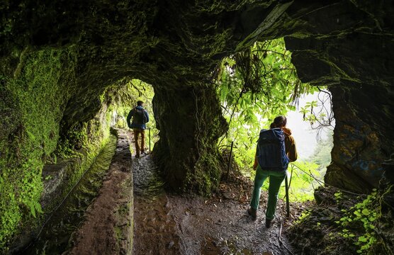 Hiker in a tunnel at PR9 Levada do Caldeir&atilde;o Verde, Madeira, Portugal