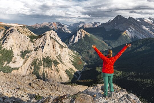 Female hiker with raised arms looking from summit over mountain landscape, summit with orange Sulphur deposits, panoramic view, Sulphur Skyline Trail, Nikassin Range, near Miette Hotsprings, Jasper National Park, British Columbia, Canada
