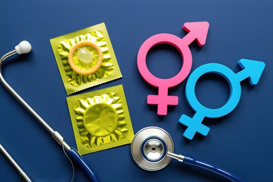 Safe sex symbols pink female blue male and condoms with stethoscope on blue background. Health awareness concept for safe intercourse pregnancy prevention.