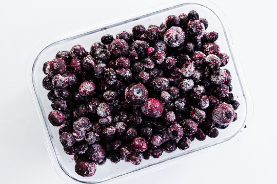 close up of frozen blueberries with ice crystals in glass container