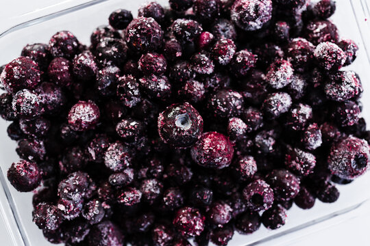 close up of frozen blueberries with ice crystals in glass container