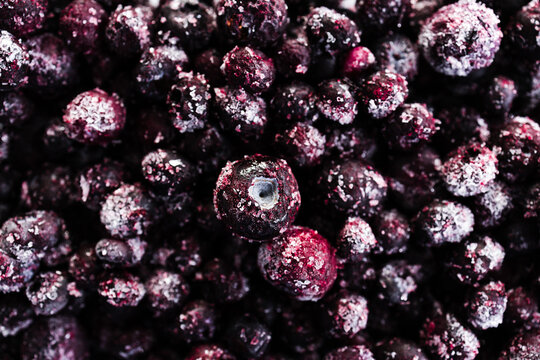 close up of frozen blueberries with ice crystals in glass container
