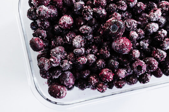 close up of frozen blueberries with ice crystals in glass container