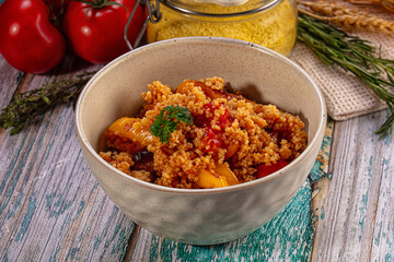 Fototapeta premium Couscous with roasted vegetables in ceramic bowl on rustic wooden table