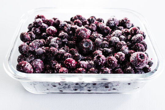 close up of frozen blueberries with ice crystals in glass container