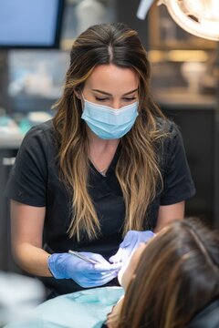 Dental hygienist provides oral care to a patient in a modern dental clinic during a routine check-up using safety equipment like gloves and masks