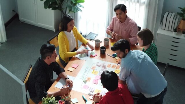 Top down view of diverse people brainstorming and making scrum task board. Group of skilled business team working together and using kanban board while shake hands for making agreement. Convocation.
