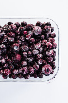 close up of frozen blueberries with ice crystals in glass container