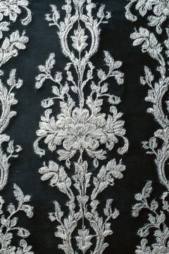 Intricate fabric overlay pattern displayed on a dark background showcasing detailed floral and vine designs with clear craftsmanship and textile art