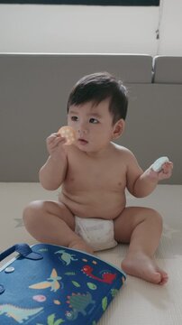 4K Cute Asian baby boy playing with busy board toy at home, early childhood development.