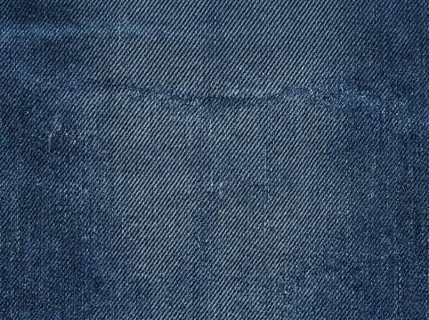 Dark indigo denim fabric texture close-up. Twill weave textile background for fashion design and apparel manufacturing.