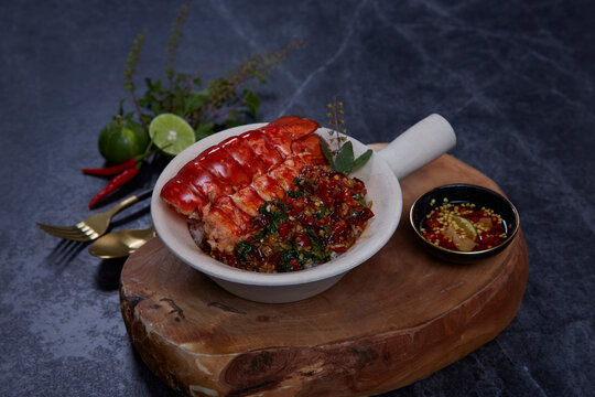 Spicy stirred fried lobster with basil leaves on jasmine rice on black background. Thai food.
