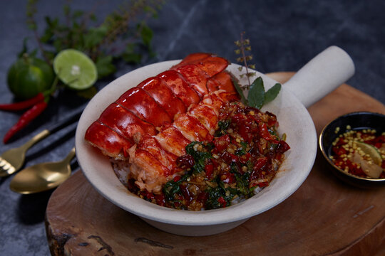 Spicy stirred fried lobster with basil leaves on jasmine rice on black background. Thai food.
