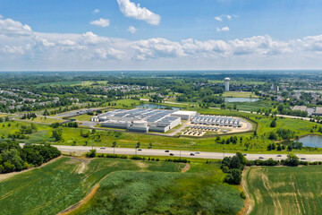 Naklejka na ściany i meble Aerial view of the data center complex, large AI center structure surrounded by roads and green countryside areas 
