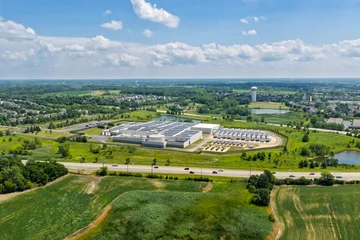 Aerial view of the data center complex, large AI center structure surrounded by roads and green countryside areas  © marchello74