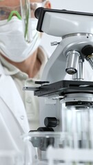 Naklejka premium Scientist wearing personal protective equipment viewing a slide through a microscope's eyepiece