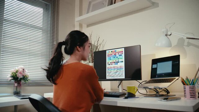 Young creative woman working on a computer in her home office. A professional designer choosing colors from a palette on her screen