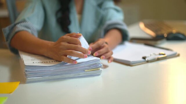 Cropped shot woman Reviewing Stack of Contract Documents at Office Desk with Clipboard and Smartphone