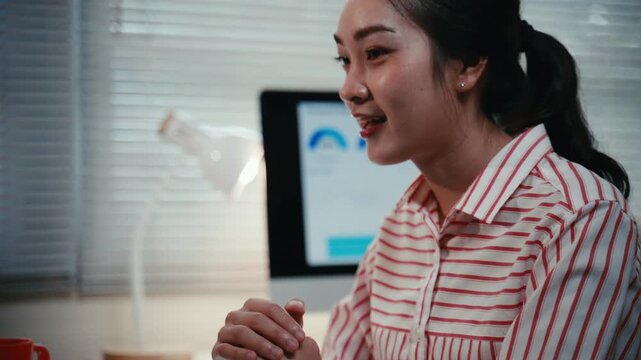 Closeup of a young asian business woman enthusiastically talking and explaining a project during a video conference in the office at night