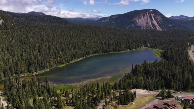 Aerial of Leech Lake in Wenatchee National Forest in Central Washington in summer with dense coniferous trees and Spiral Butte in the background