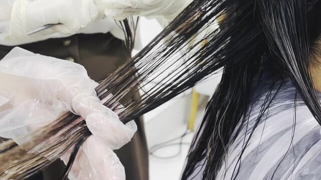 Hairdresser combing wet hair with comb and gloves in salon, close-up of hair treatment, horizontal commercial beauty footage