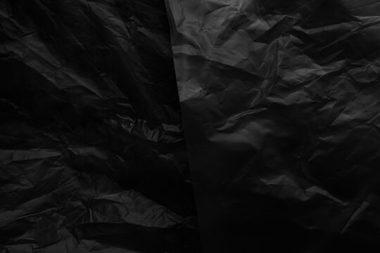 Black background plastic wrinkle bag film glossy crumpled overlay package rough wrap material pack reflection texture floor packaging retail grain pollution trash polyethylene, halloween backdrop.