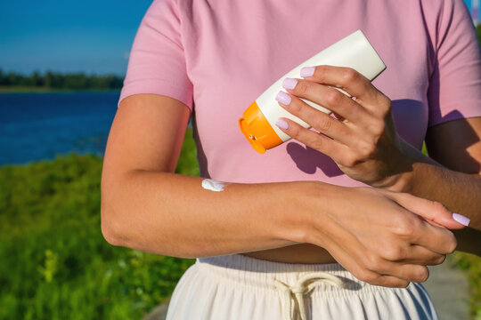 Woman applying sunscreen cream on arm outdoors, UV protection skincare and healthy summer skin concept