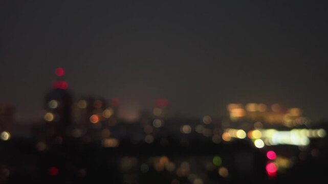 Defocused night city skyline with colorful bokeh lights under stormy overcast sky before thunderstorm